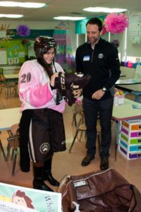 Miss Healey gets into hockey gear with some assistance from Bryan Helmer